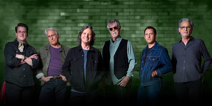 Nitty Gritty Dirt Band members in front of a green brick wall.