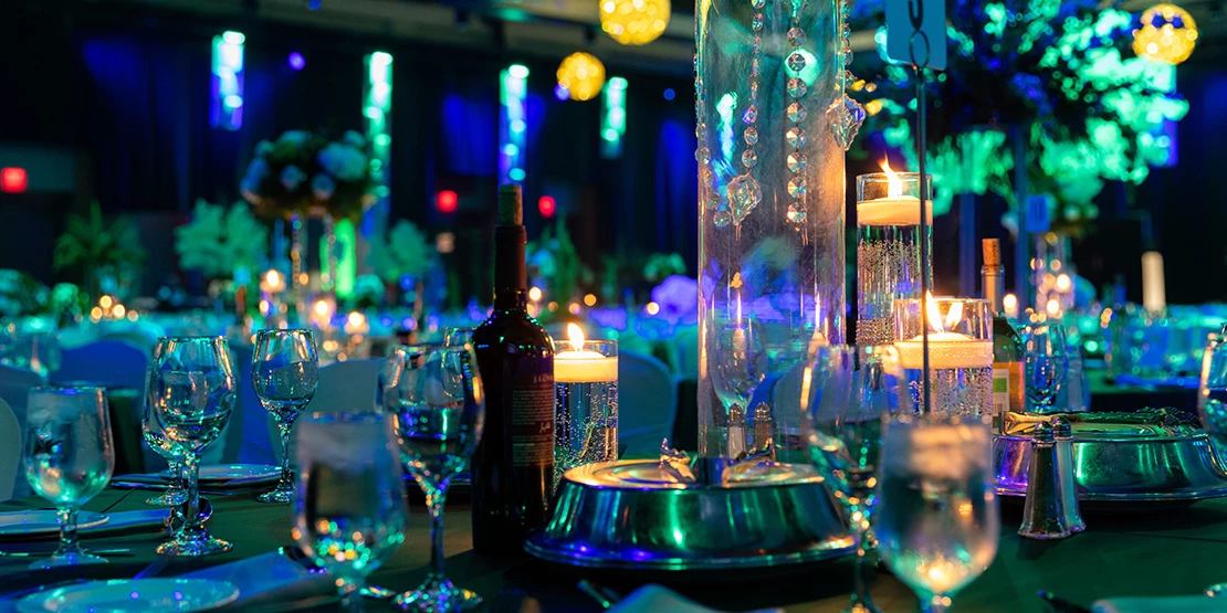 Closeup image of a wine bottle and glasses on a table with bright decorations.